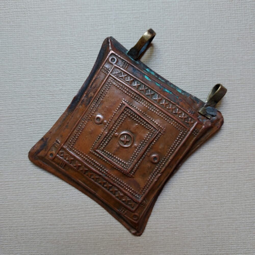 Tuareg tcherot amulet made of copper with a fine repoussé pattern from Niger.Tuareg tcherot amulet made of copper with a fine repoussé pattern from Niger.Tuareg tcherot amulet made of copper with a fine repoussé pattern from Niger.Tuareg tcherot amulet made of copper with a fine repoussé pattern from Niger.